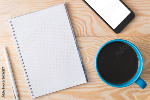 a cup of coffee, a phone and a notebook on a wooden background