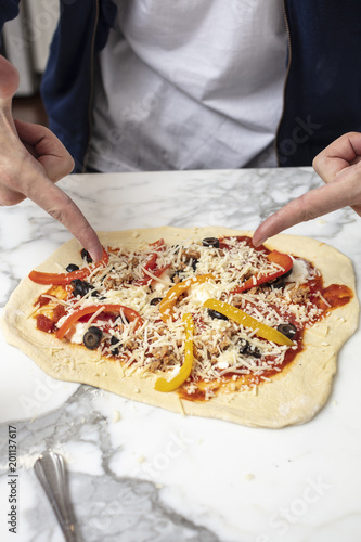 Man pointing at homemade pizza before baking in the oven