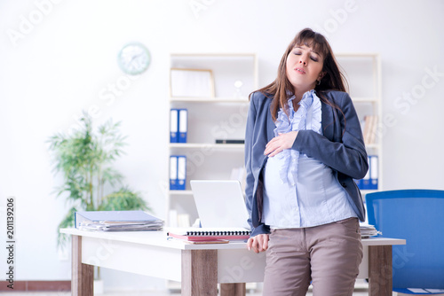 Pregnant woman struggling to do work in office