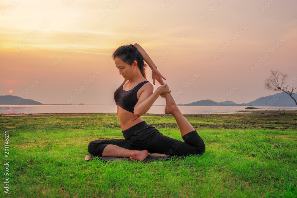 The Yoga woman is relax with beautiful sunset background on the fresh grass as floor.