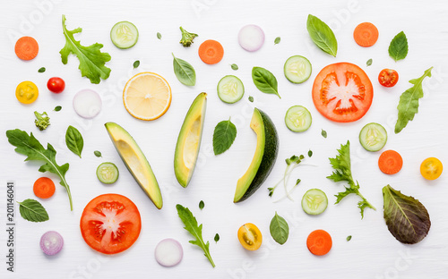 Food pattern with raw ingredients of salad. Various vegetables lettuce leaves, cucumbers, tomatoes, carrots, broccoli, basil ,onion and lemon flat lay on white wooden background.