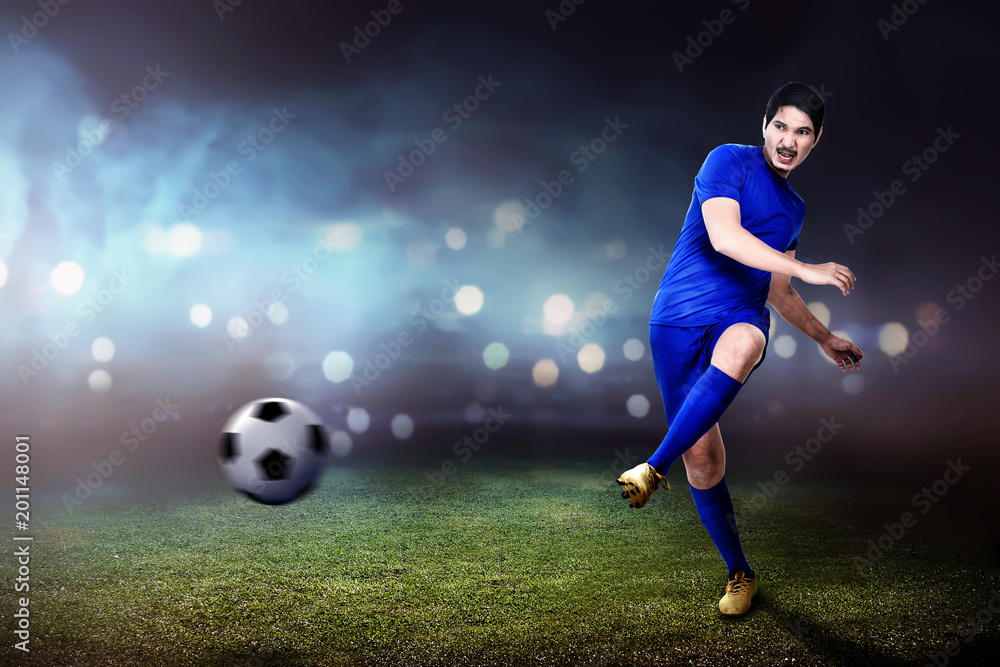 Young asian footballer man kicking the ball