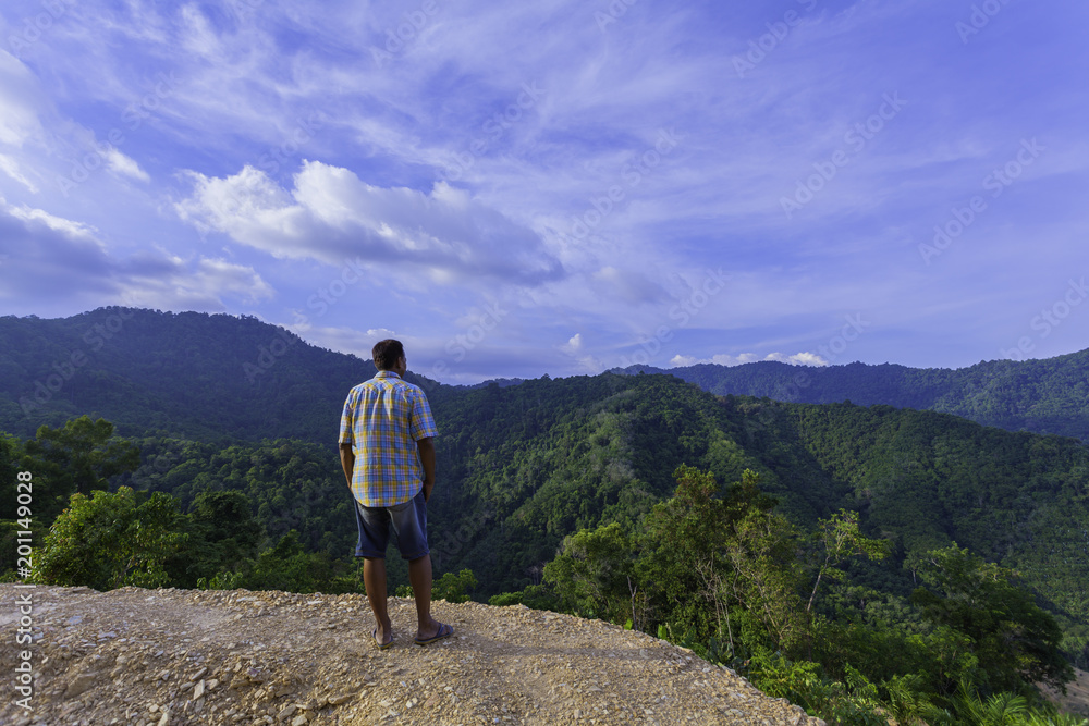 a man standing on hilltop look around the valley