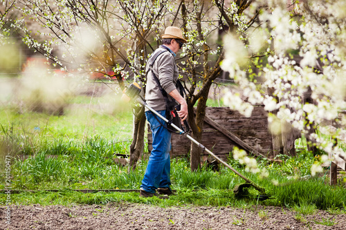 man cutting grass in garden with the weed trimmer