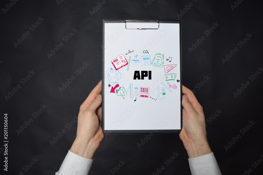 In the hands of a businessman a notebook with the inscription:API