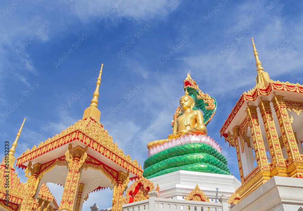 Fototapeta premium big golden buddha statue sitting under green thai dragon statue in thai temple on blue sky