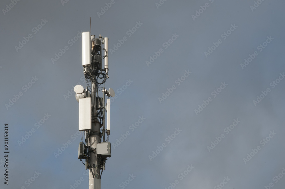 Cell tower closeup against a white sky.