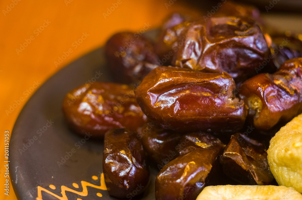 dried dates and figs in a ceramic plate on a wooden table