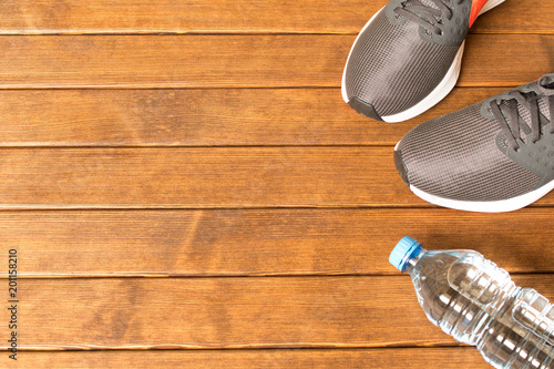 Running sneakers, water bottle on wooden background . With empty space for text