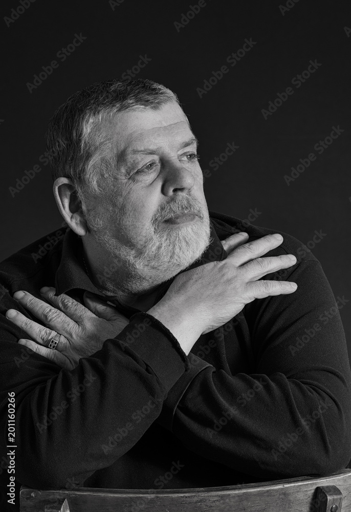 Black and white low key portrait of bearded Caucasian senior man meditating in darkness Black and white low key portrait of bearded Caucasian senior man meditating in darkness