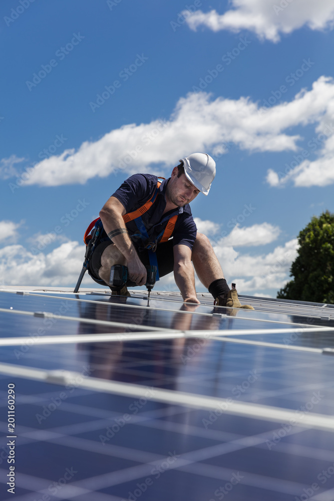 Solar panel technician with drill installing solar panels - obrazy, fototapety, plakaty 