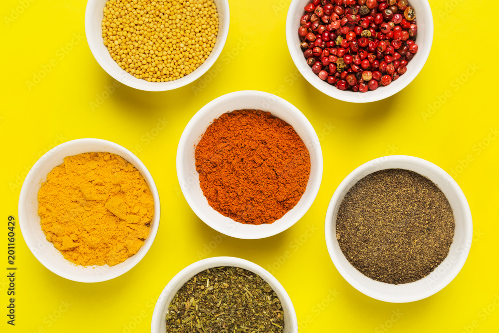 Various spices in bowls on yellow background. Top view. Food background Various spices in bowls on yellow background. Top view. Food background