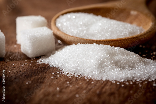 Photo Close up a sugar cubes and cane in wooden spoon on the table