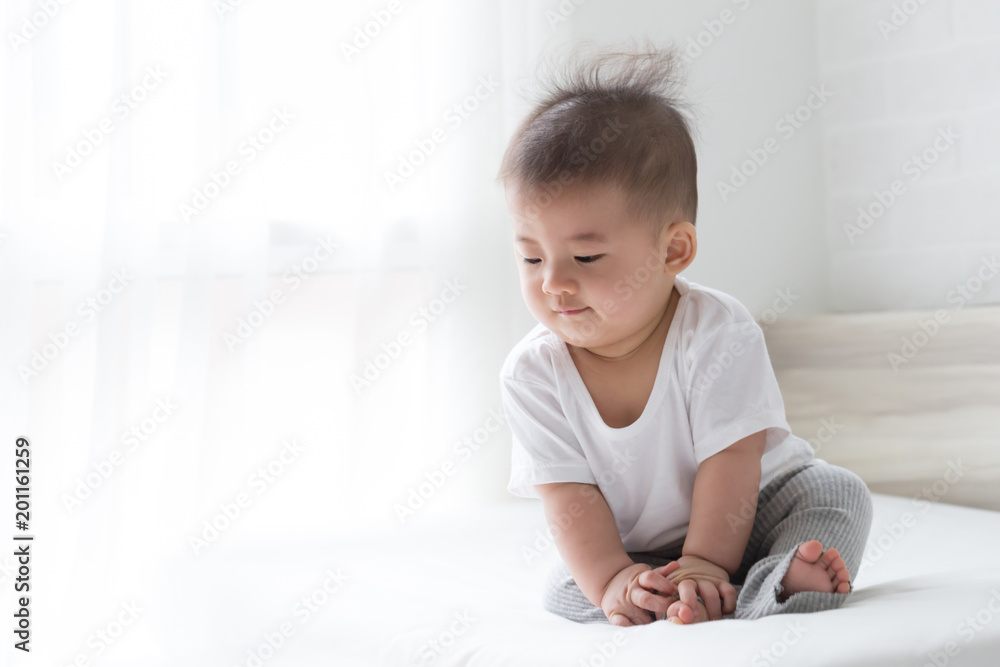 Asian baby boy looking something on white bed Asian baby boy looking something on white bed
