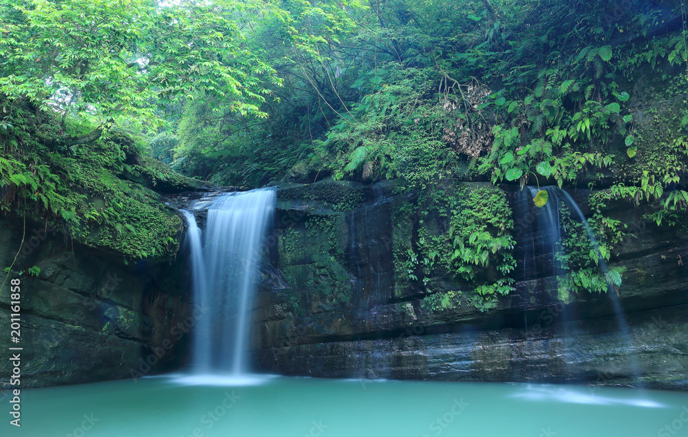 A cool refreshing waterfall tumbling down the cliff into an emerald pond hidden in a mysterious forest of lush greenery ~ Scenic view of a beautiful waterfall and intriguing river potholes in Taiwan