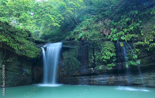 A cool refreshing waterfall tumbling down the cliff into an emerald pond hidden in a mysterious forest of lush greenery ~ Scenic view of a beautiful waterfall and intriguing river potholes in Taiwan