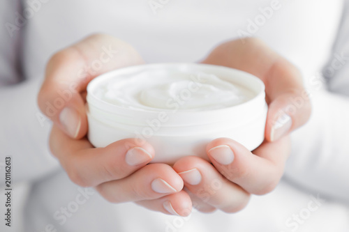 Beautiful groomed woman's hands holding a white cream jar. Moisturizing cream for clean and soft skin. Healthcare concept.