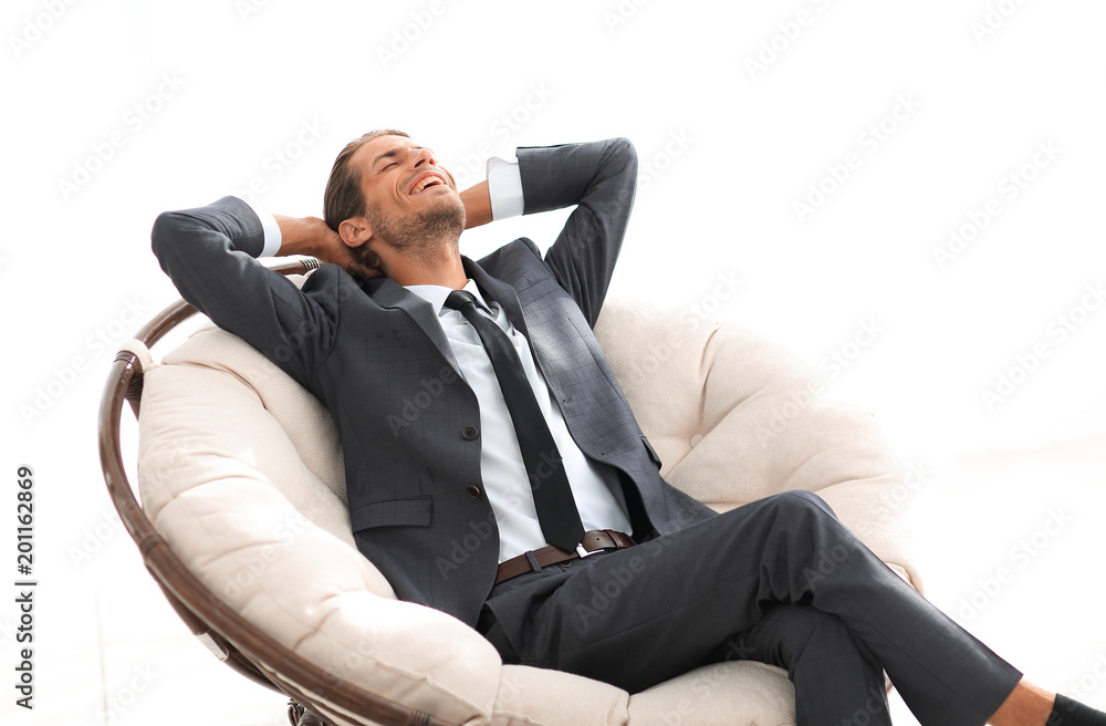young businessman meditating in big comfortable armchair