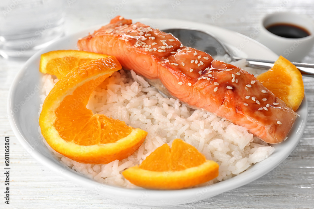 Fish fillet served with rice and orange slices in bowl Fish fillet served with rice and orange slices in bowl