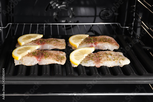 Pieces of raw fish with lemon in oven