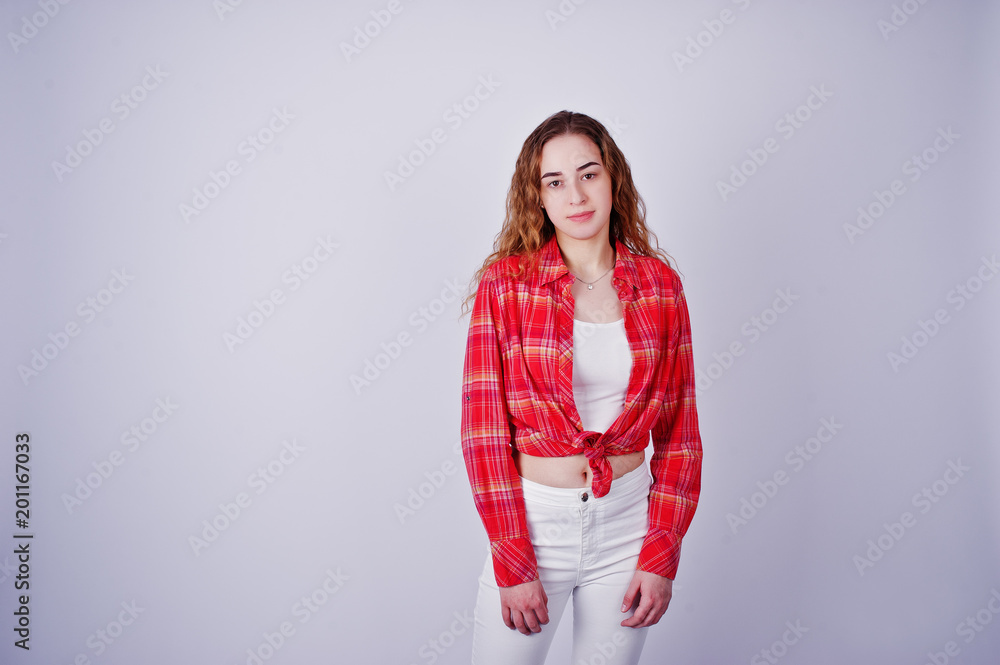 Young girl in red checked shirt and white pants against white background on studio. Young girl in red checked shirt and white pants against white background on studio.