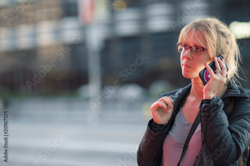 Beautiful girl talking on the phone at night on a busy city street looking preplexed and weary photo