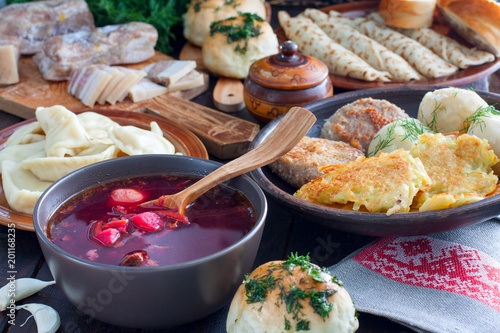 Traditional food in the Ukrainian cuisine - borsch, vareniki, bacon, broth, nalgovniki, cutlets in Kiev, dranniki, pampushki, on a wooden table, selective focus, top view