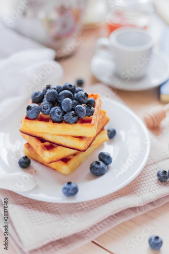 Belgian waffles with blueberries on the light wooden table. Healthy breakfast. 