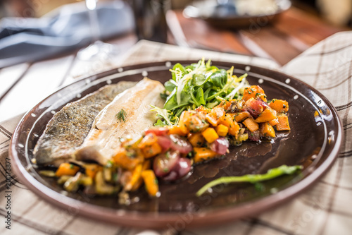 Roasted fish fillet with pumpkim pieces and herb decoration in pub or restaurant