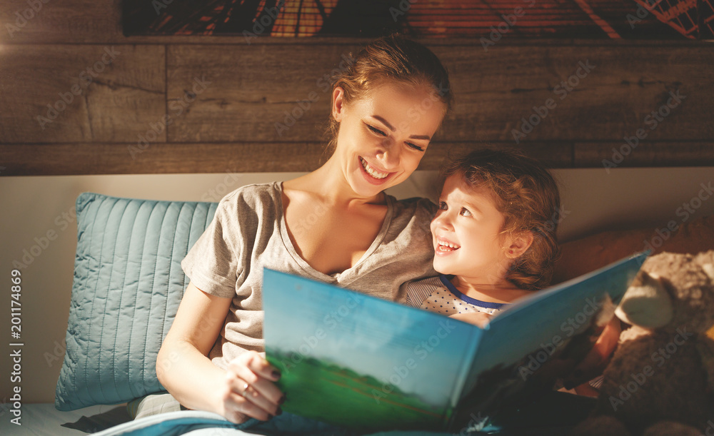 mother and child reading book in bed before going to sleep . StockFoto