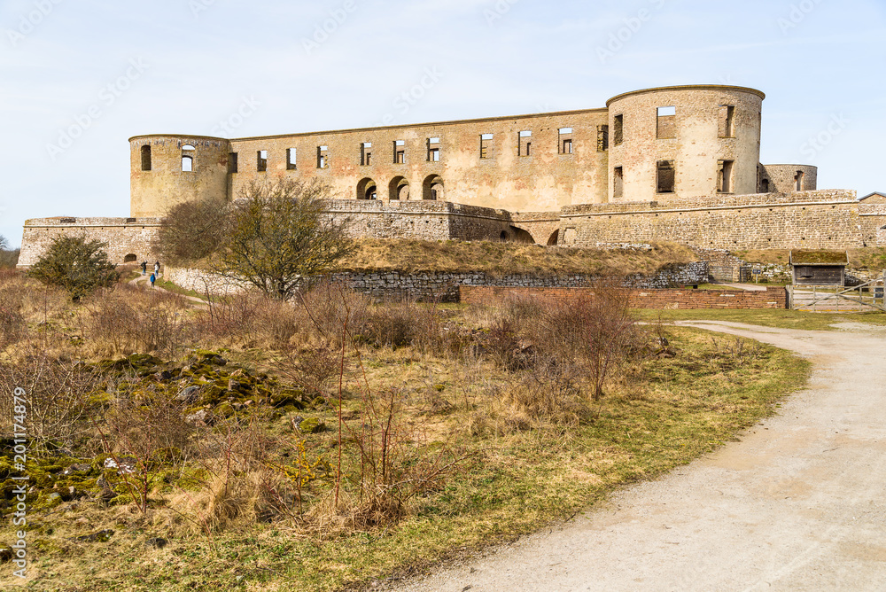 Historic castle ruin at Borgholm, Oland in Sweden. Gravel road leading up toward the ruin. People walking on the road facing away from camera. A popular travel destination with historic values.