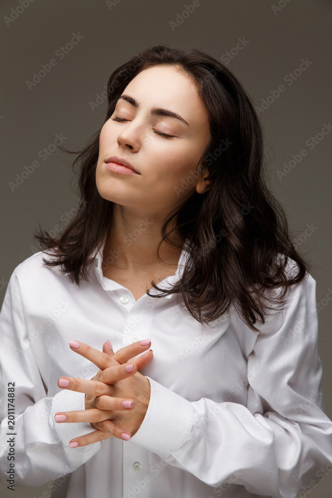 Beautiful girl in a white shirt shows emotions - hope. On a light background. Beautiful girl in a white shirt shows emotions - hope. On a light background.