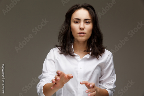 Beautiful girl in a white shirt shows emotions. On a light background.