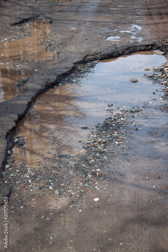 Wallpaper Mural The bad asphalted road. Big pothole filled with water. Dangerous destroyed roadbed. Torontodigital.ca
