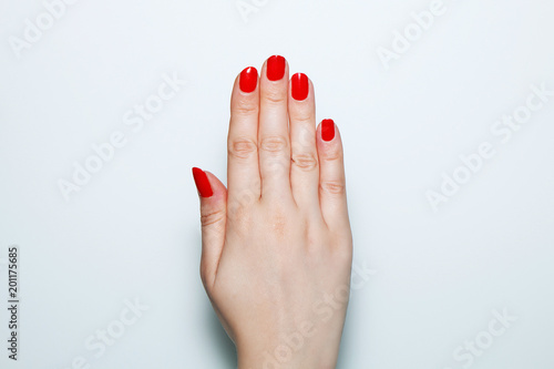 Female hand with red nails painted on a white background