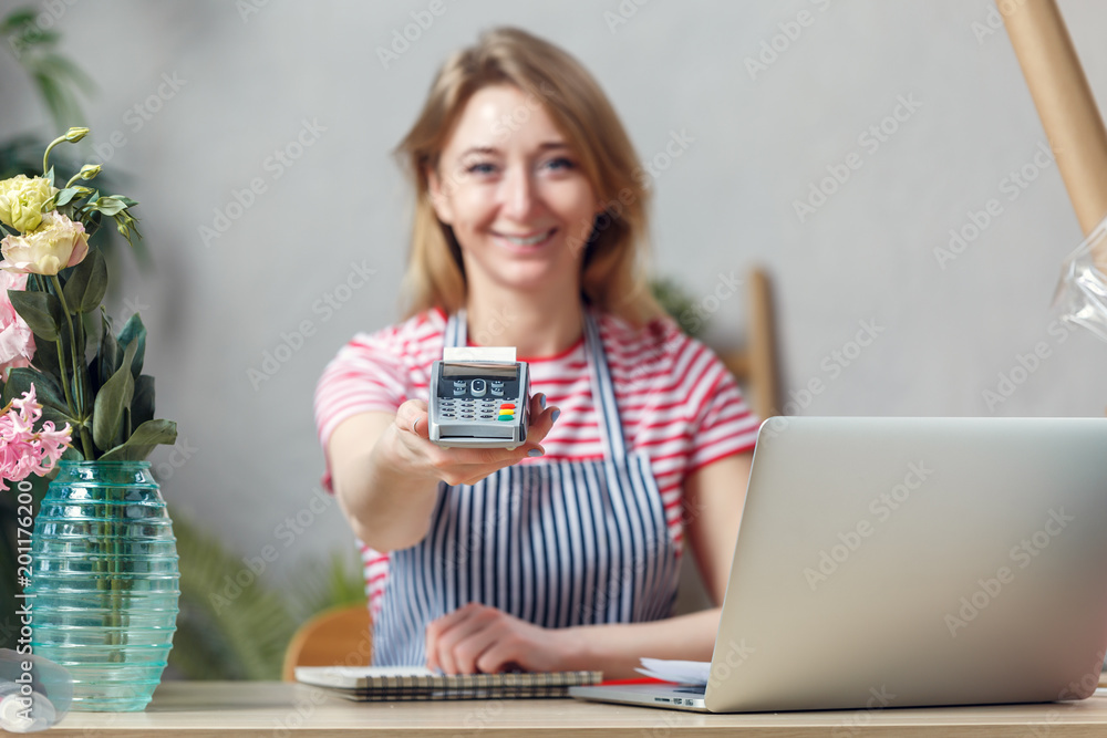 Image of florist with calculator at table with laptop Image of florist with calculator at table with laptop