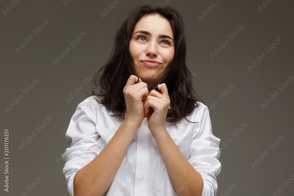 Beautiful girl in a white shirt shows emotions - fun. On a light background. Beautiful girl in a white shirt shows emotions - fun. On a light background.