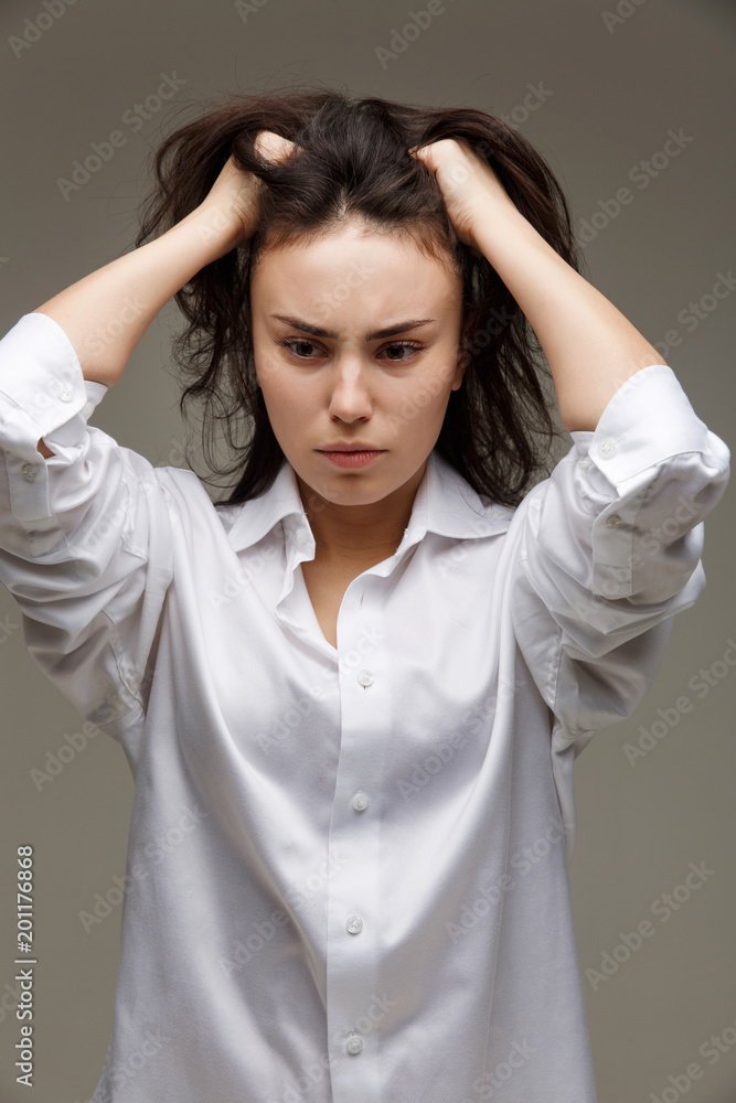 Beautiful girl in a white shirt shows emotions - headache. On a light background. Beautiful girl in a white shirt shows emotions - headache. On a light background.