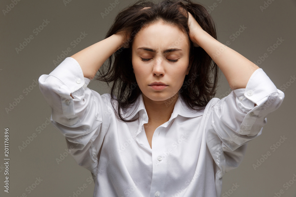Beautiful girl in a white shirt shows emotions - thoughtfulness. On a light background. Beautiful girl in a white shirt shows emotions - thoughtfulness. On a light background.