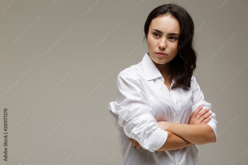 Beautiful girl in a white shirt shows emotions - disorder. On a light background. Beautiful girl in a white shirt shows emotions - disorder. On a light background.