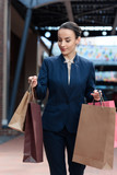 attractive businesswoman looking at shopping bags in hands