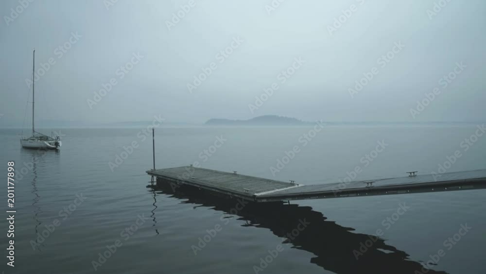 Angled shot of a lake pier, one boat nearby, cloudy weather. Angled shot of a lake pier, one boat nearby, cloudy weather.