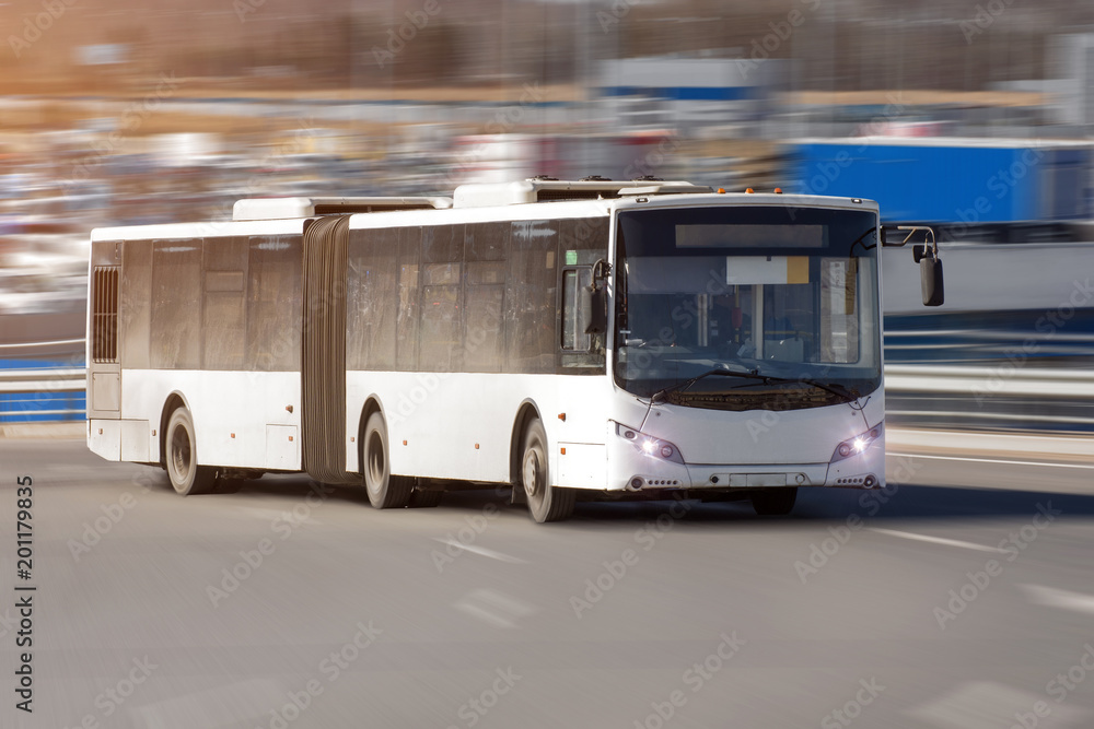 Passenger lengthened articulated bus city bus of white color rides at high speed along the highway.