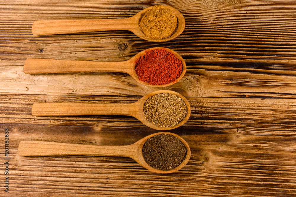 Spoons with the different spices on wooden table. Top view Spoons with the different spices on wooden table. Top view