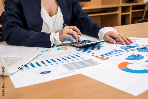 Business woman working at business graph with calculator