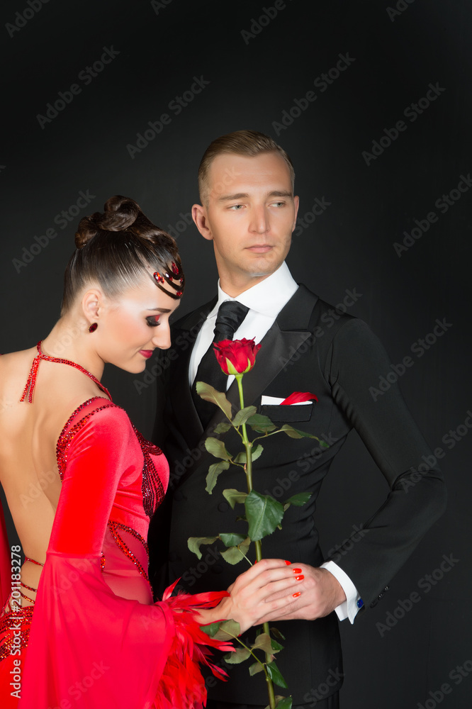 Sensual woman and man with rose flower. Woman in red dress and macho in tuxedo. Couple of ballroom dancers in love. Valentines day celebration. Love proposal and date concept Sensual woman and man with rose flower. Woman in red dress and macho in tuxedo. Couple of ballroom dancers in love. Valentines day celebration. Love proposal and date concept