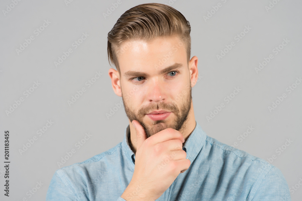 Macho with stylish hair touch beard with hand. Bearded man with healthy young skin. Guy with unshaven face and mustache. Beard grooming and hair care in barbershop. Skincare and mens beauty concept Macho with stylish hair touch beard with hand. Bearded man with healthy young skin. Guy with unshaven face and mustache. Beard grooming and hair care in barbershop. Skincare and mens beauty concept