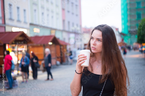 Woman with takeaway drink walk on street. Woman hold disposable coffee cup. Coffee or tea mood. Drink and food during summer vacation or travelling. Beauty girl with long hair and natural makeup