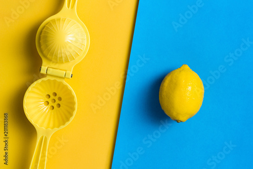 Lemon and juicer, squeezer on contrasting colored background.