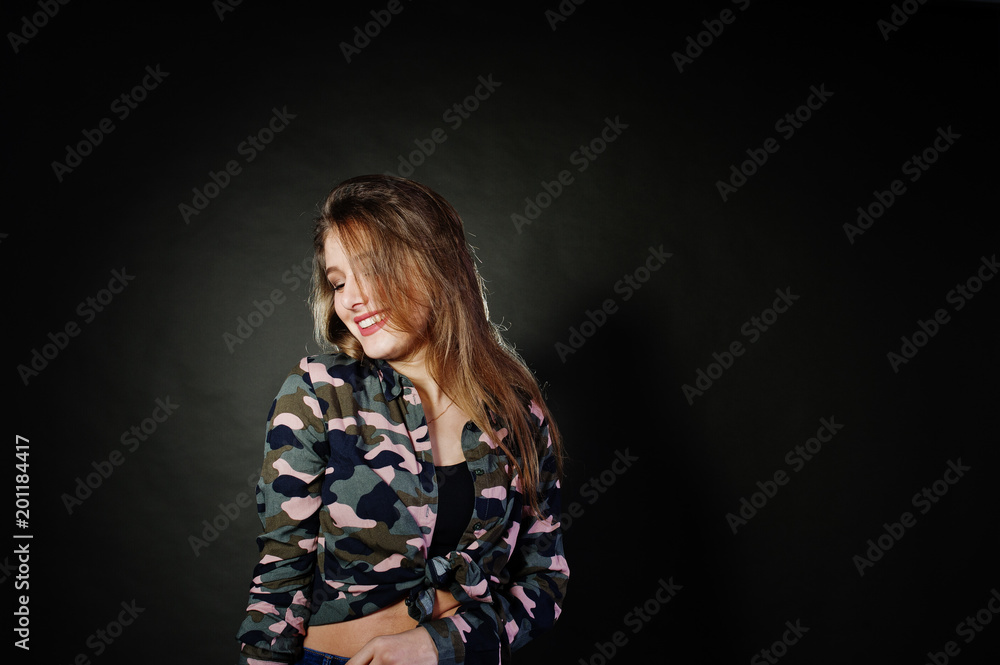 Handsome brunette girl wear military shirt and jeans, posing at studio against gray background. Studio model portrait. Handsome brunette girl wear military shirt and jeans, posing at studio against gray background. Studio model portrait.